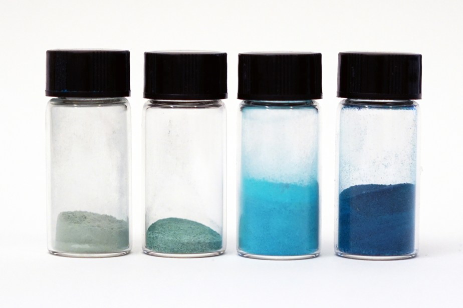 four glass vials filled with blue and green pigments