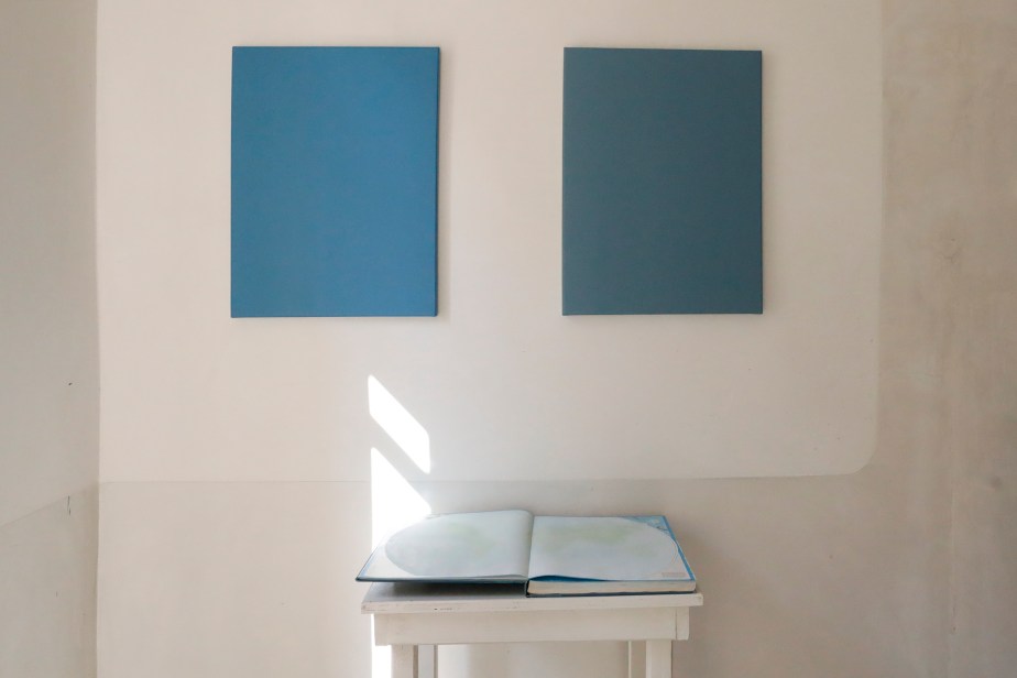 Two blue monochrome paintings and a world atlas on a plinth