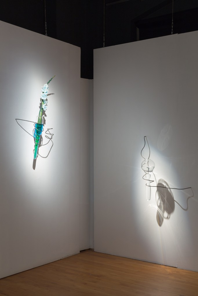 installation view of blown glass sculptures with flower and blue pigment