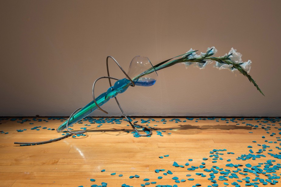 installation view of blown glass sculptures with flower and metal support on the ground